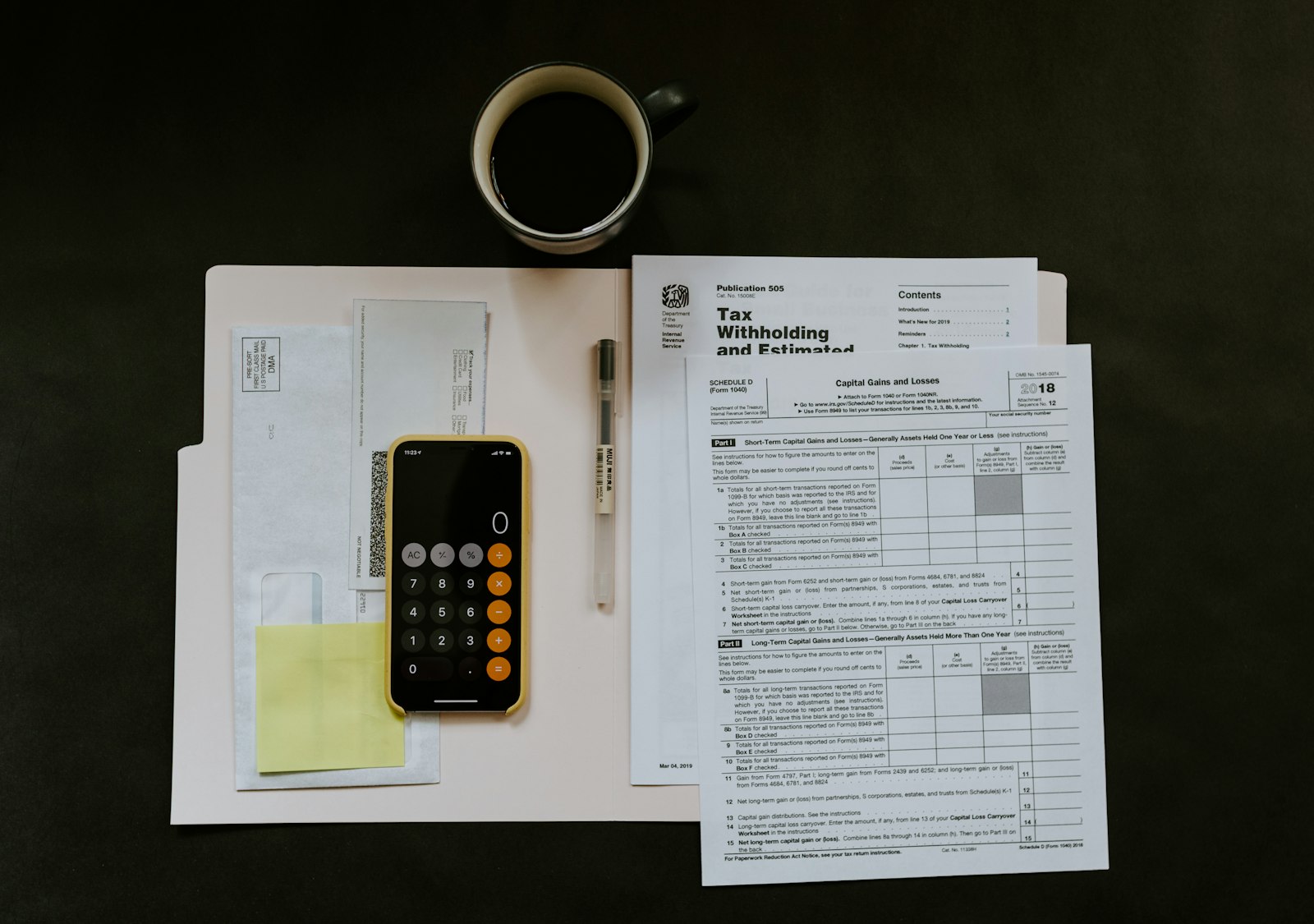 Desk covered in tax forms with a phone calculator