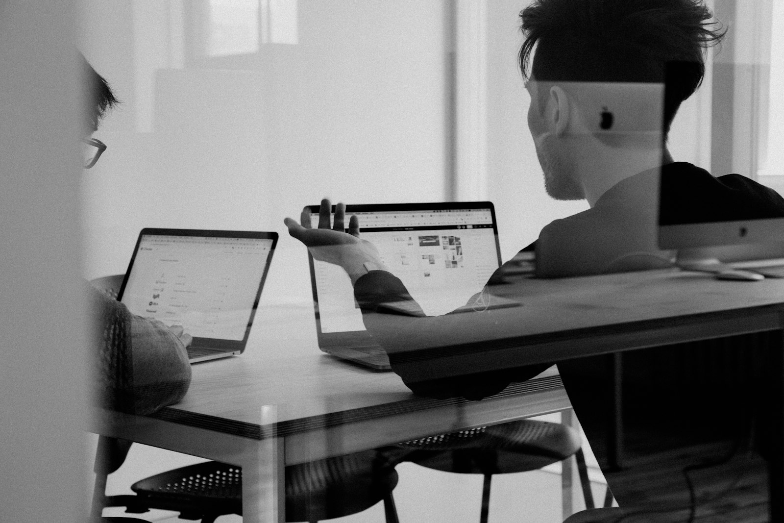 Two people working across a table with laptops