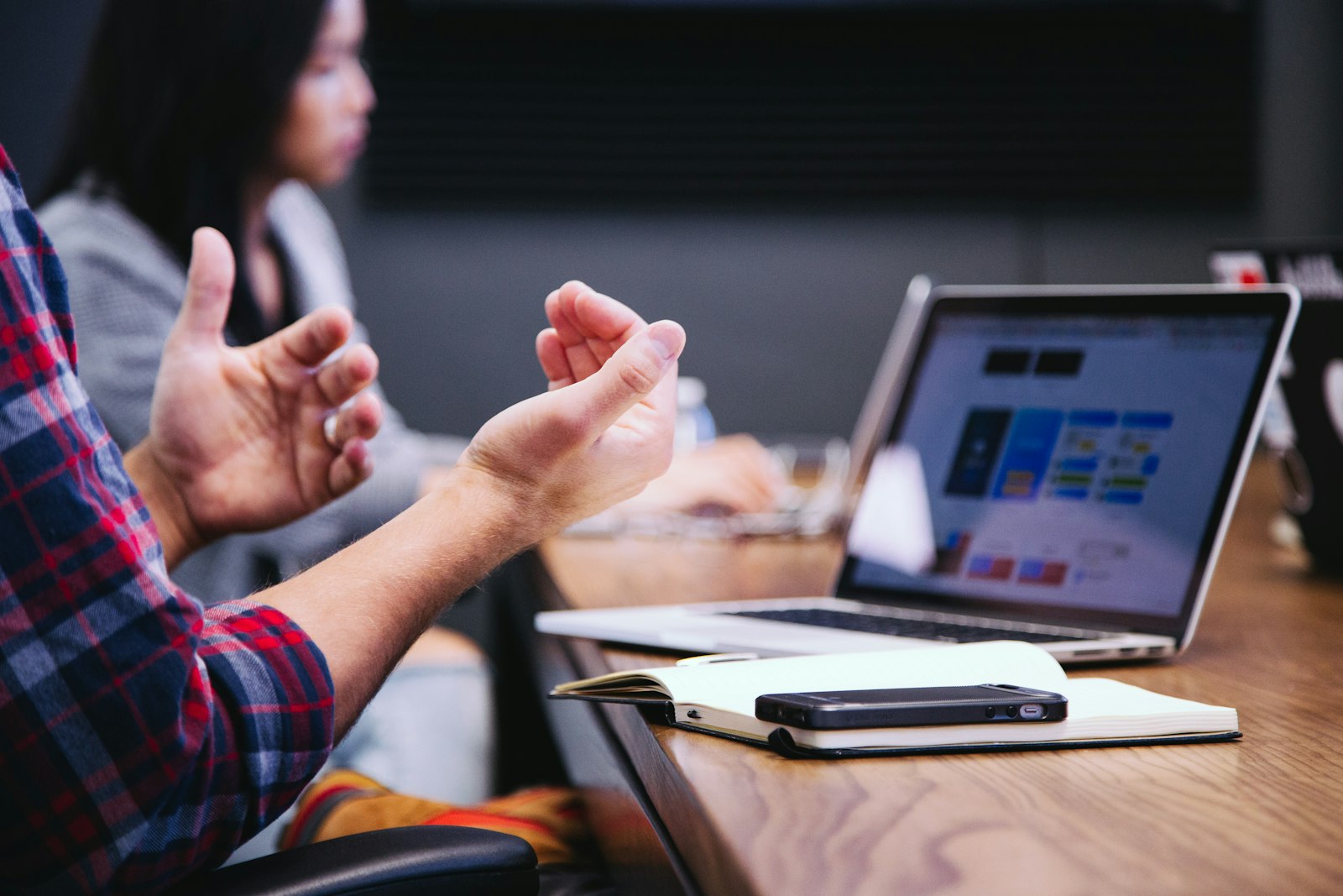 Person gesturing during a team discussion with laptops