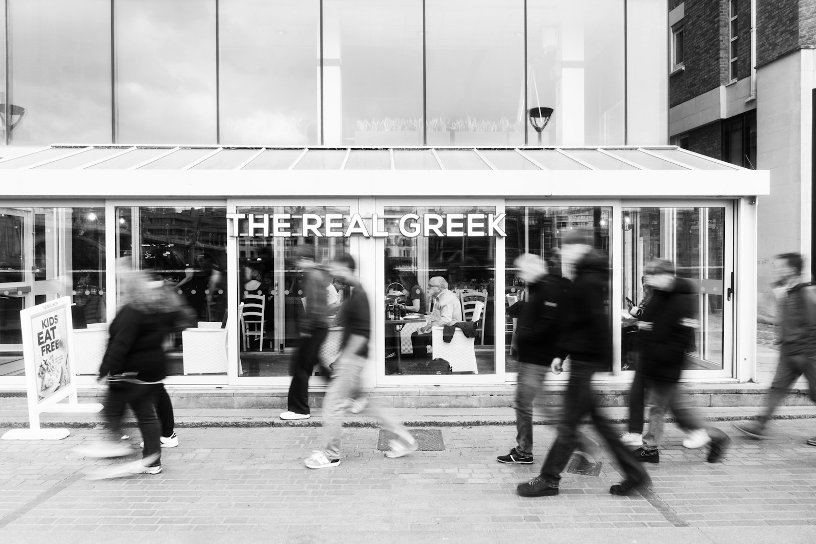 People walk past a storefront with blurred motion.