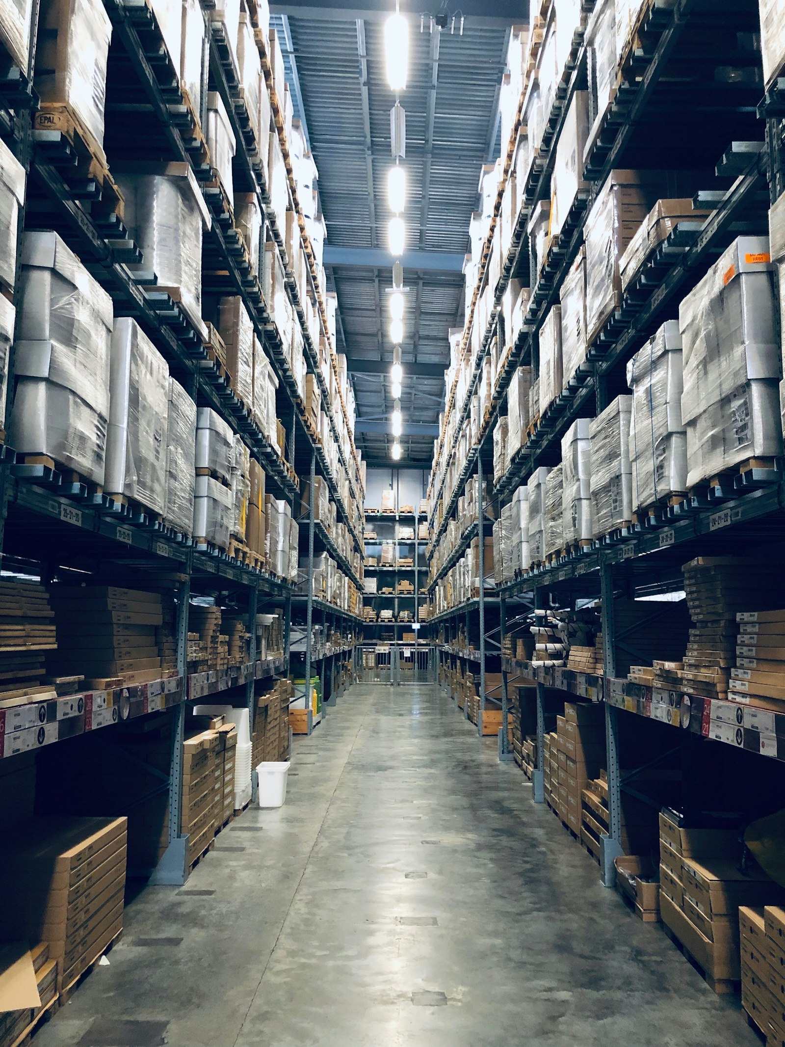 Aisle of a large warehouse with stacked shelves